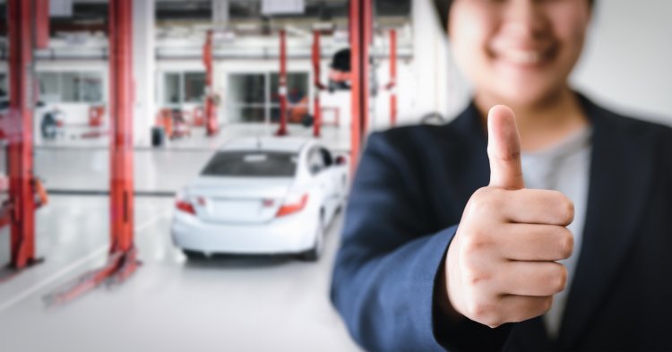 Thumbs up with car in background